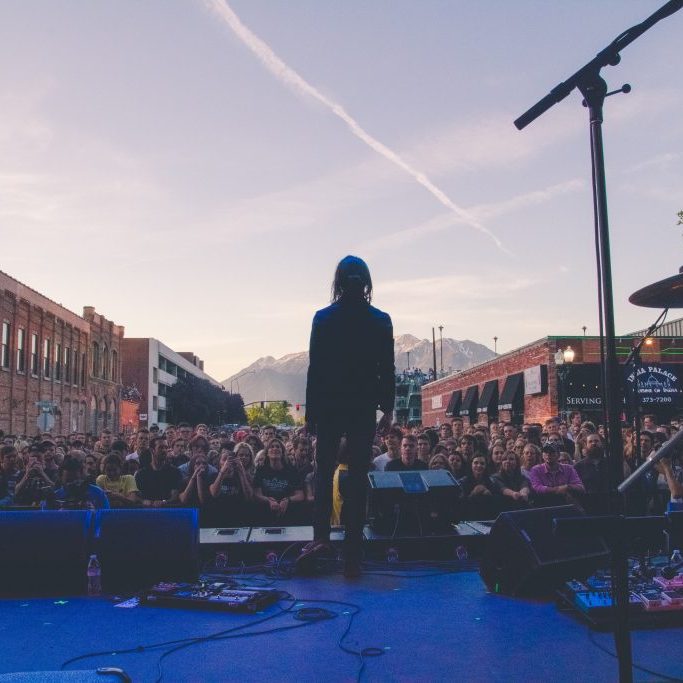 a person on stage looks out at a crowd on Provo's main street